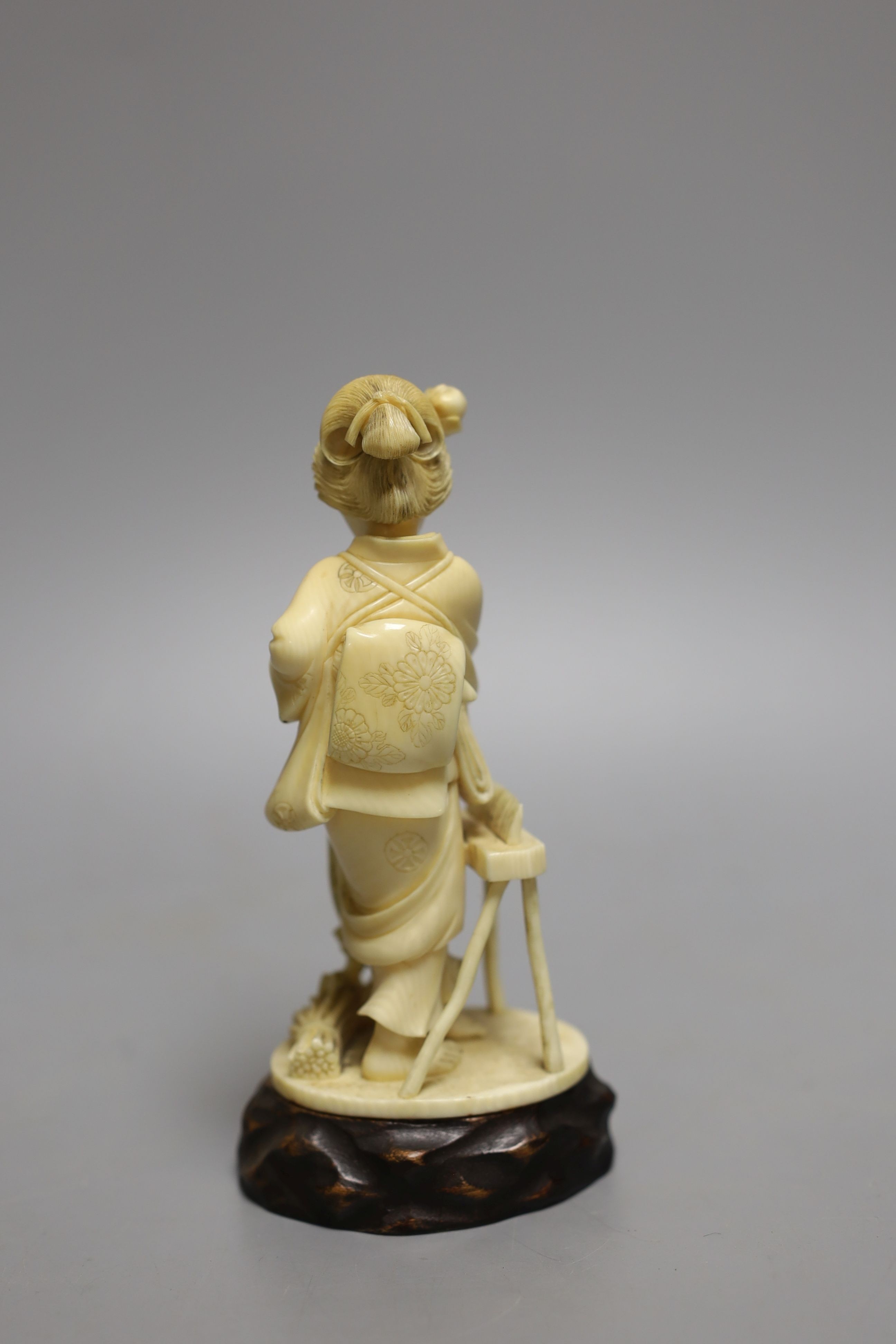 A Japanese Tokyo school carved ivory figure of a woman flailing wheat, Meiji period, wood stand - 14.5cm tall (including stand)